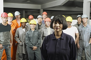 men and woman wearing suits and hard hats inside gray room